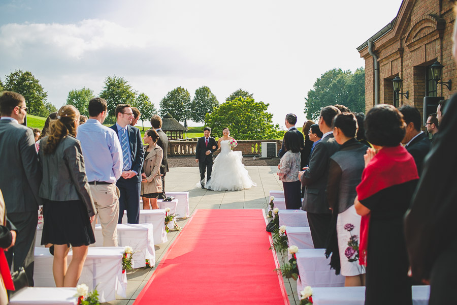 Bei der freien Trauung auf der Terrasse vom Kosaido in Düsseldorf wird die Braut von ihrem Vater über einen roten Teppich zum Bräutigam geführt